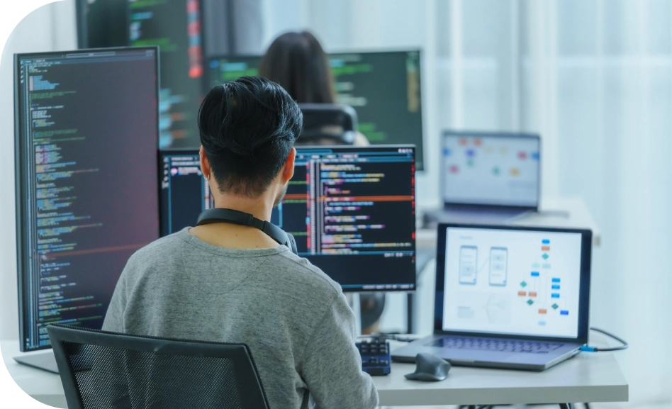 Software developer writing code on multiple screens in modern off