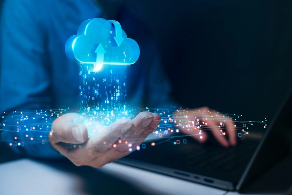 Person using laptop with holographic cloud computing symbol representing data storage and digital technology"
